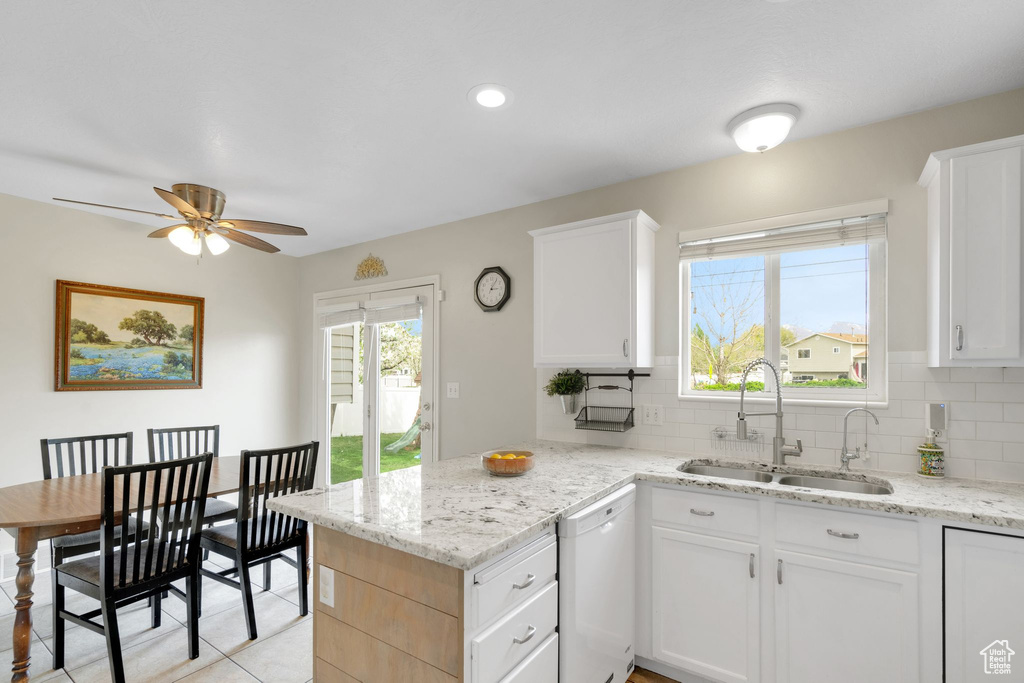 Kitchen with a sink, a peninsula, white dishwasher, a ceiling fan, and backsplash