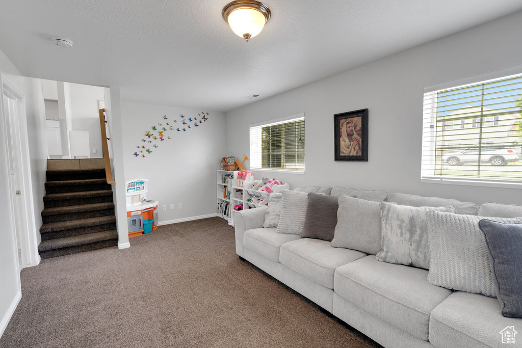 Living room featuring baseboards, carpet, and stairway