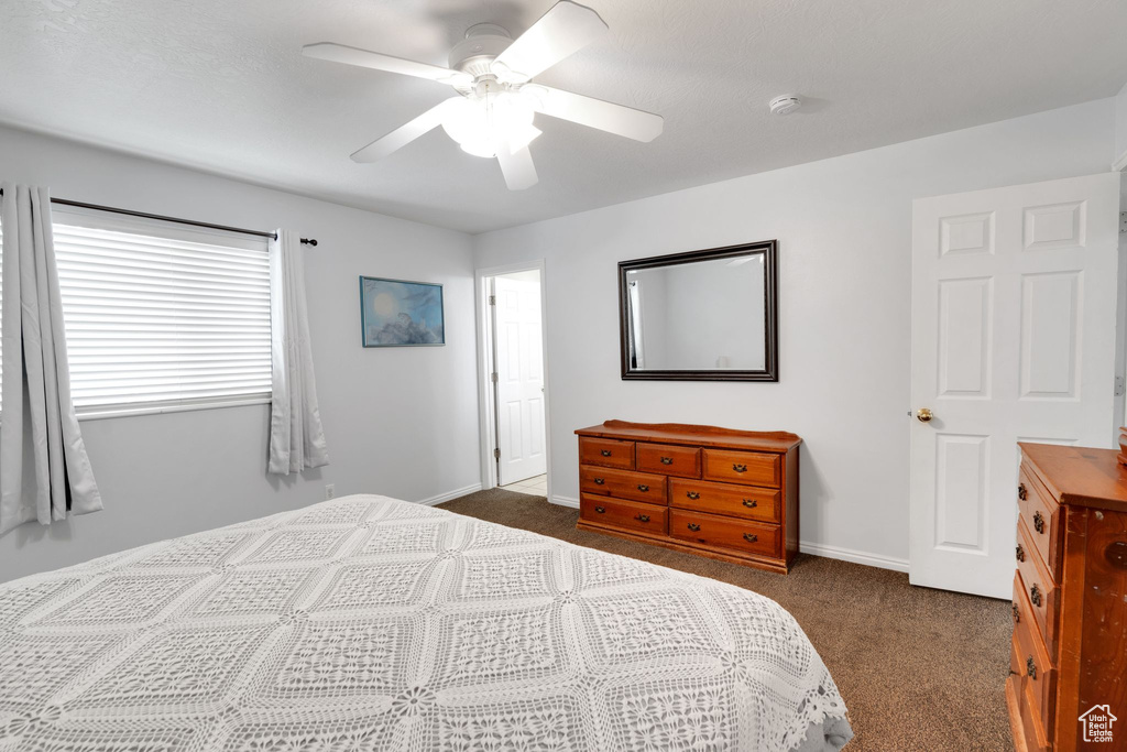 Bedroom featuring dark colored carpet, a ceiling fan, and baseboards