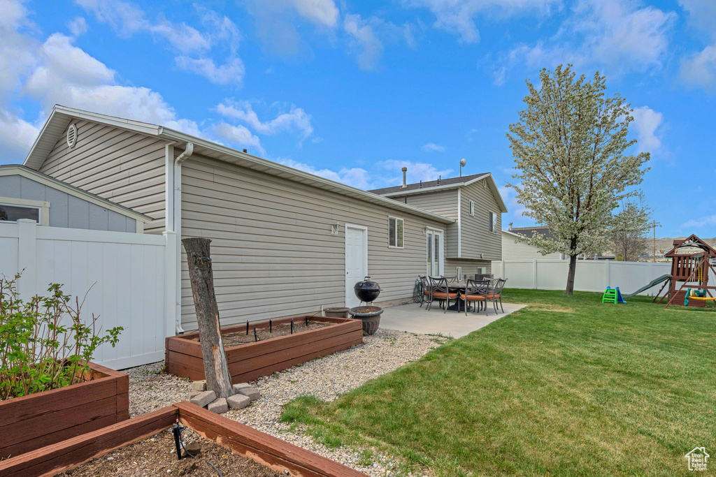 Rear view of property with fence private yard, a vegetable garden, a playground, a yard, and a patio