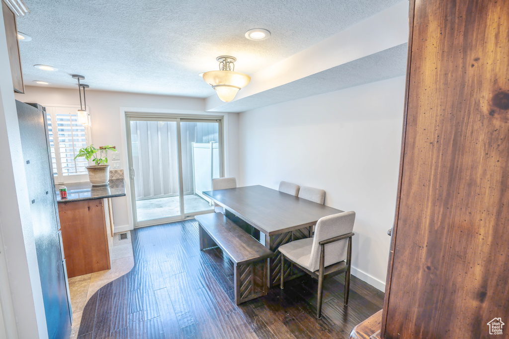 Dining room with dark wood-style flooring, a textured ceiling, recessed lighting, baseboards, and visible vents