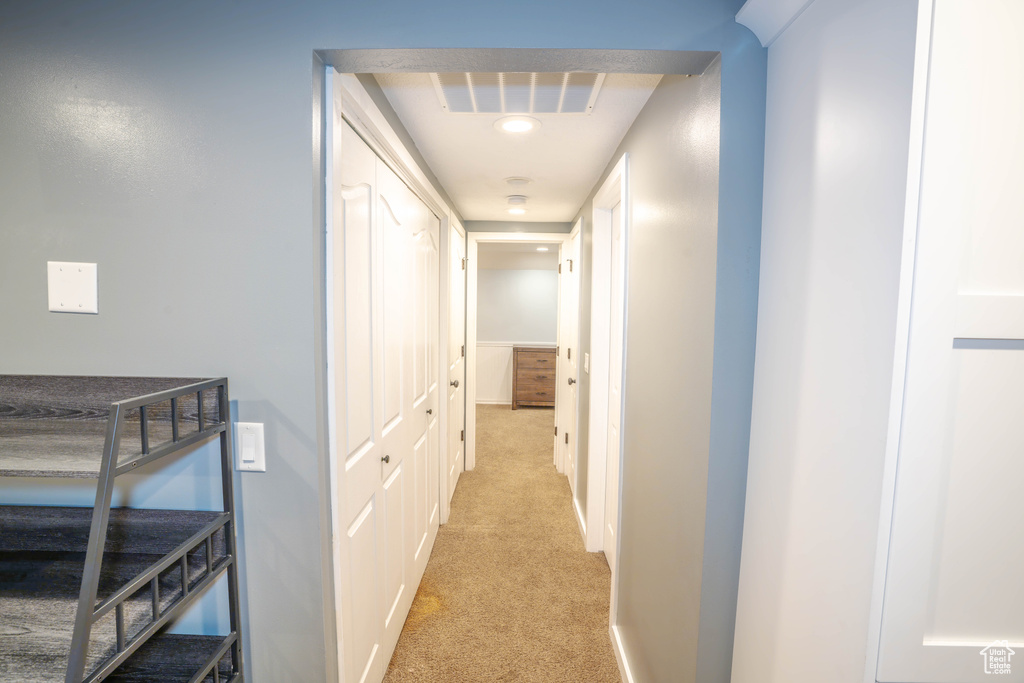 Hall featuring baseboards, light colored carpet, and visible vents