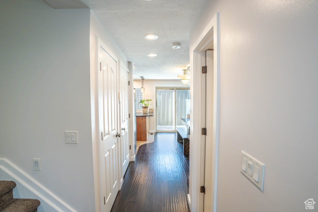 Hallway with dark wood-style flooring, a textured ceiling, stairs, baseboards, and recessed lighting