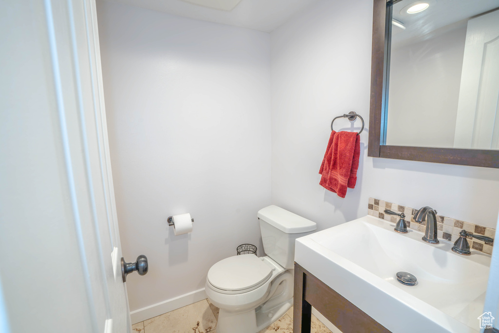 Bathroom featuring toilet, baseboards, and vanity