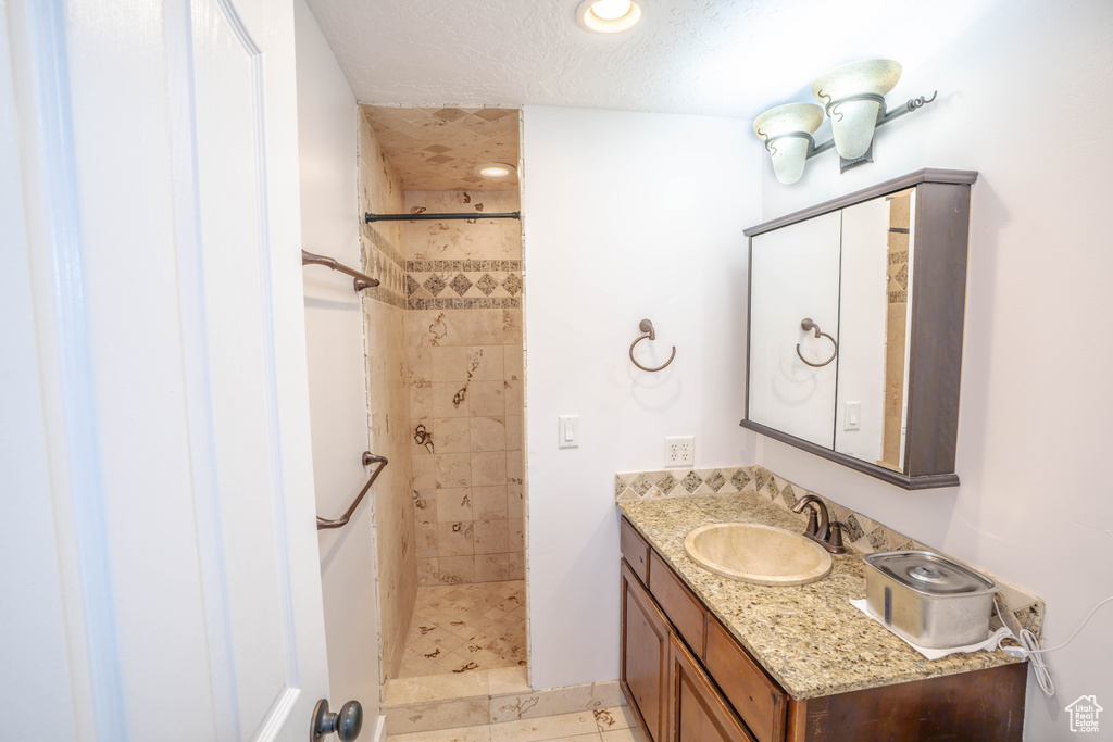 Bathroom featuring vanity, recessed lighting, a textured ceiling, and tiled shower