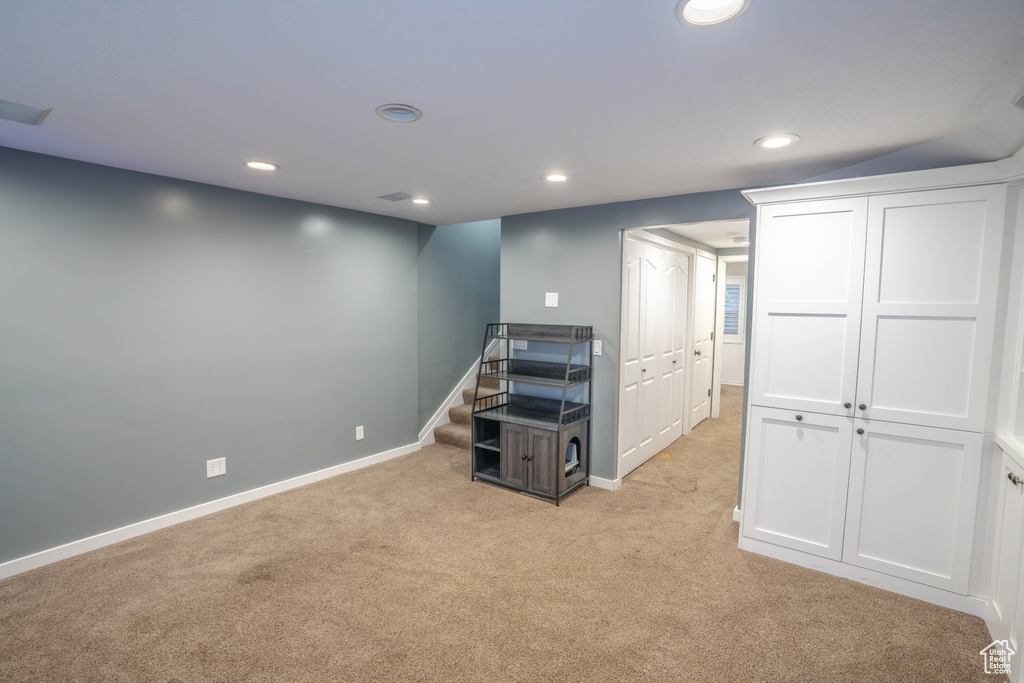 Below grade area featuring light colored carpet, recessed lighting, baseboards, and stairs