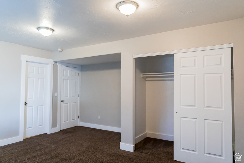 Unfurnished bedroom with multiple closets, baseboards, and dark carpet