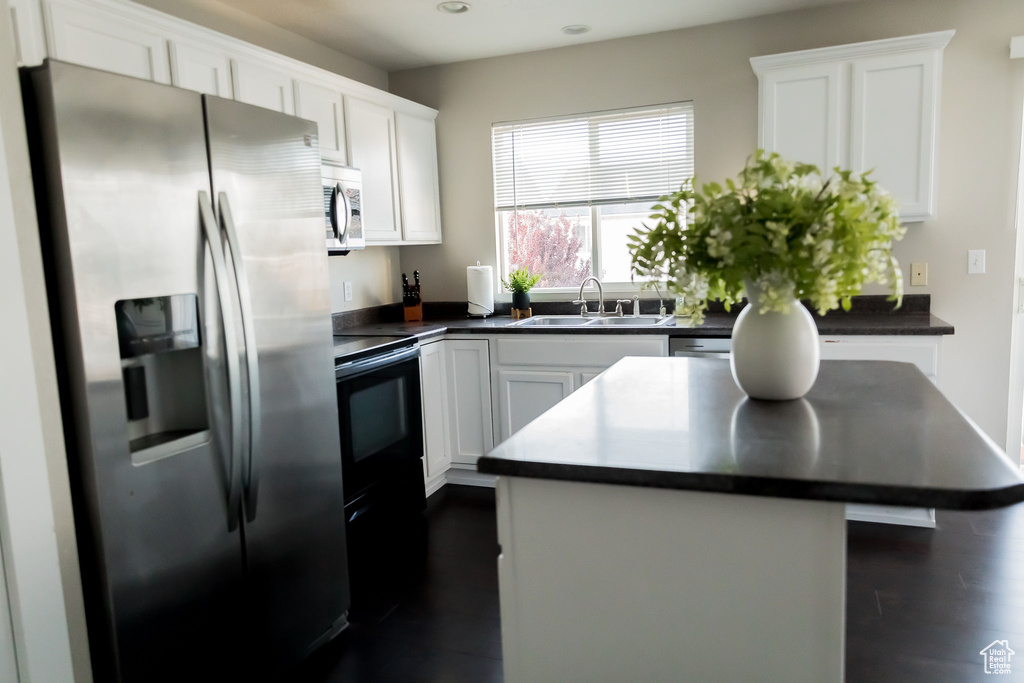 Kitchen featuring a sink, white cabinets, dark countertops, and stainless steel appliances