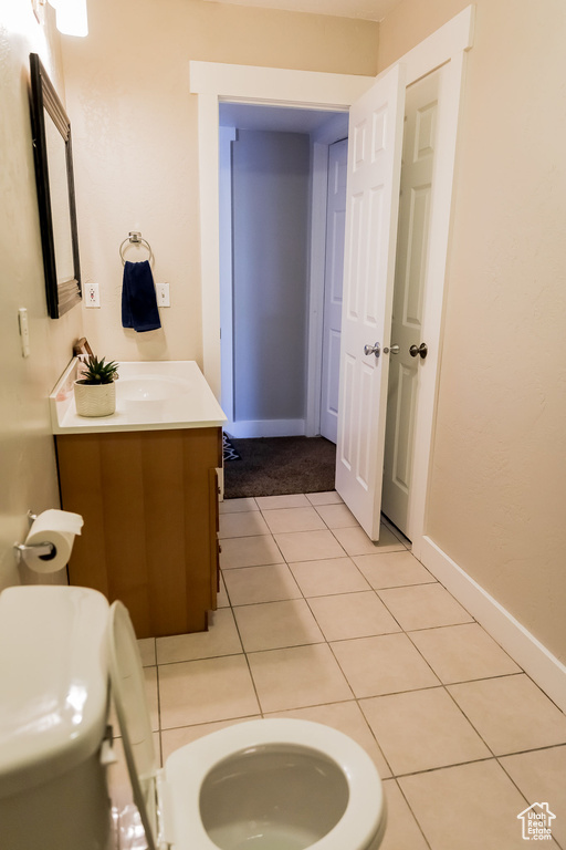 Bathroom featuring vanity, baseboards, tile patterned flooring, and toilet
