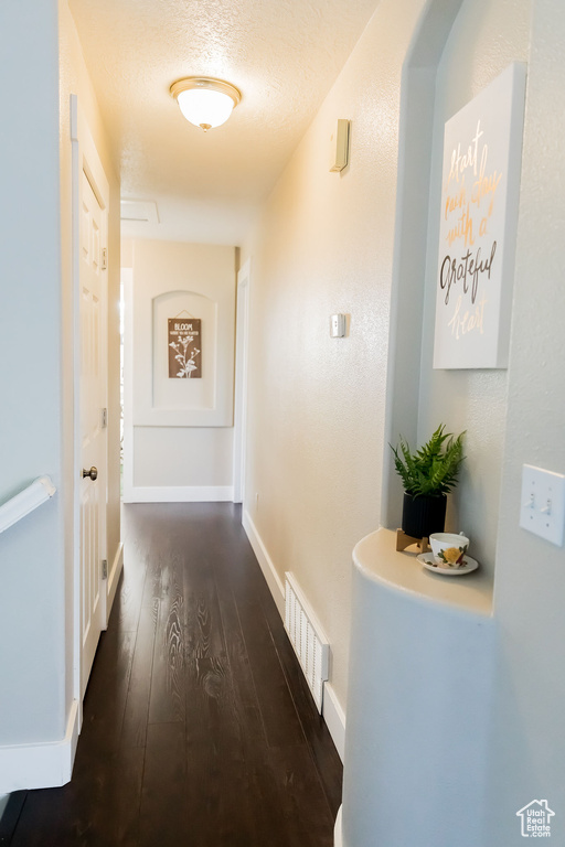 Hall with visible vents, baseboards, and hardwood / wood-style flooring