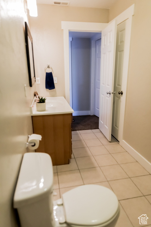 Half bath with vanity, tile patterned flooring, toilet, and visible vents