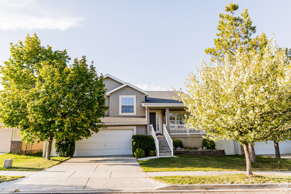View of front of home with stairs, a garage, stucco siding, a front yard, and concrete driveway