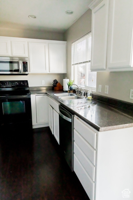 Kitchen with a sink, white cabinetry, appliances with stainless steel finishes, and dark countertops