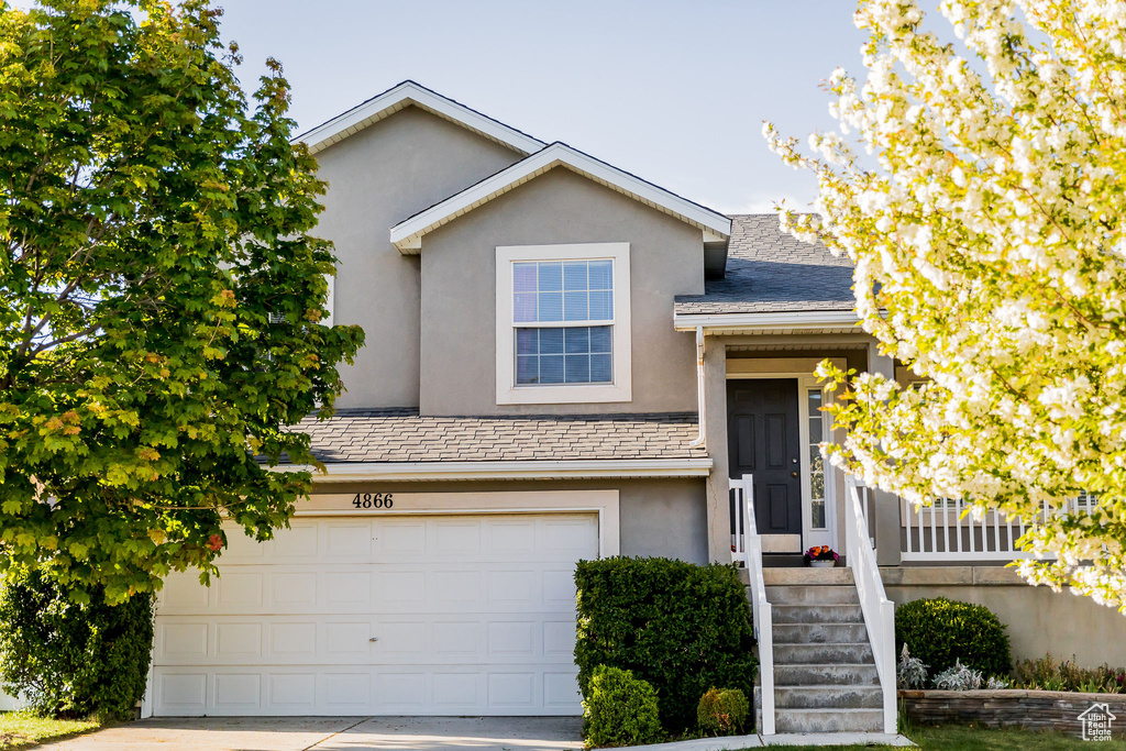 View of front of house featuring concrete driveway, an attached garage, and stucco siding