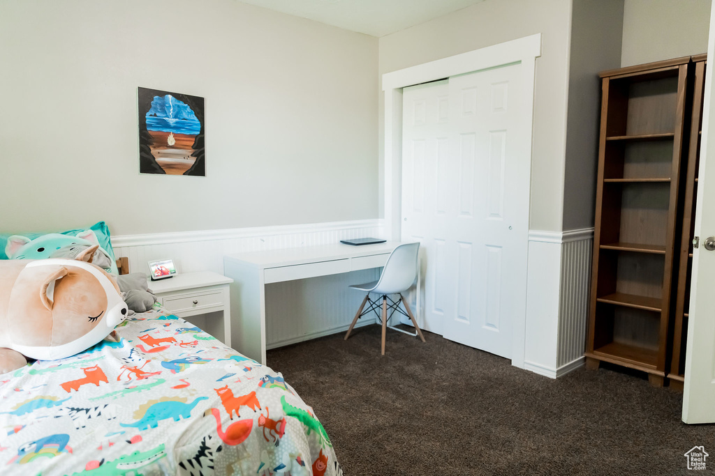 Bedroom with dark colored carpet and wainscoting