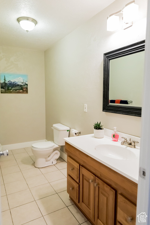 Bathroom with toilet, tile patterned floors, and vanity