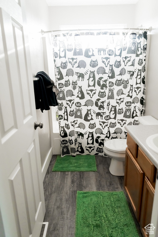 Bathroom featuring visible vents, curtained shower, wood finished floors, vanity, and toilet
