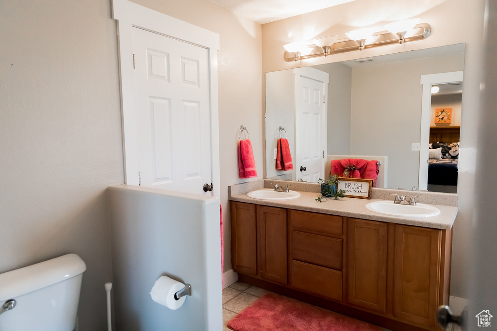 Bathroom with double vanity, toilet, a sink, and tile patterned floors