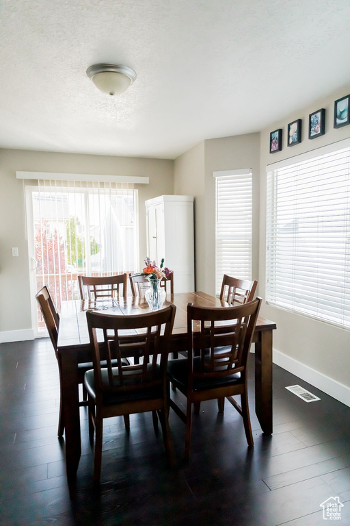 Dining area featuring baseboards, dark wood-style flooring, a textured ceiling, and visible vents