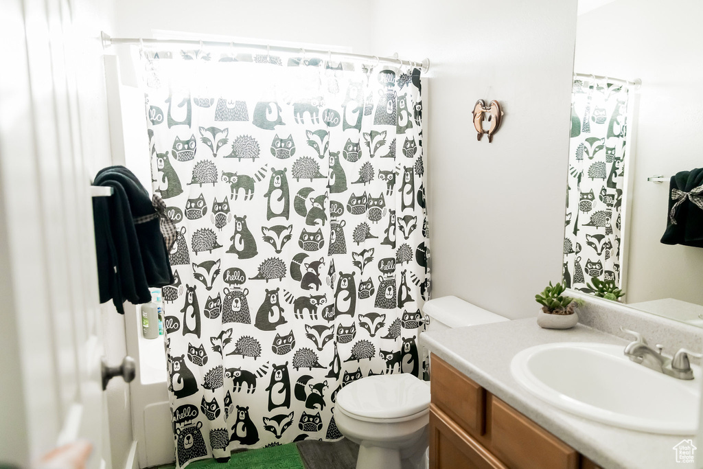 Full bath with toilet, a shower with curtain, and vanity