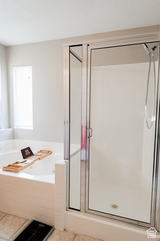 Full bathroom featuring a garden tub, tile patterned floors, and a stall shower