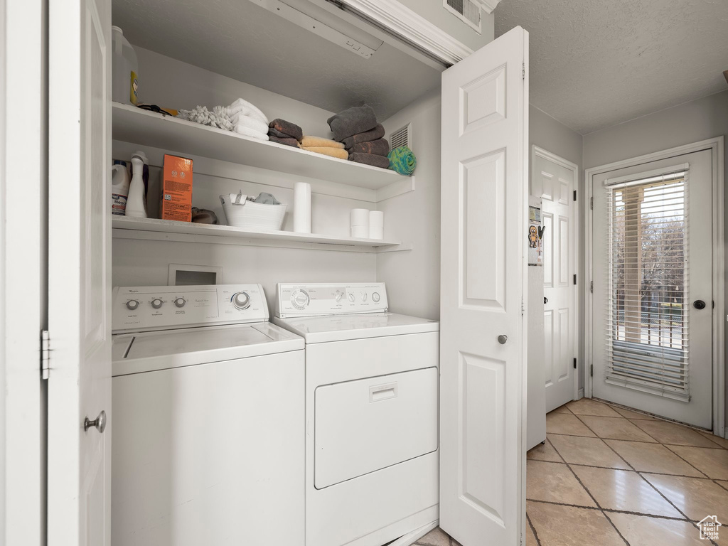 Laundry area featuring laundry area, light tile patterned floors, washing machine and dryer, and visible vents