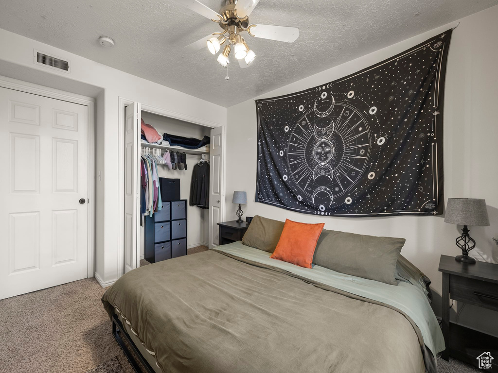 Bedroom featuring carpet floors, a textured ceiling, visible vents, and a closet