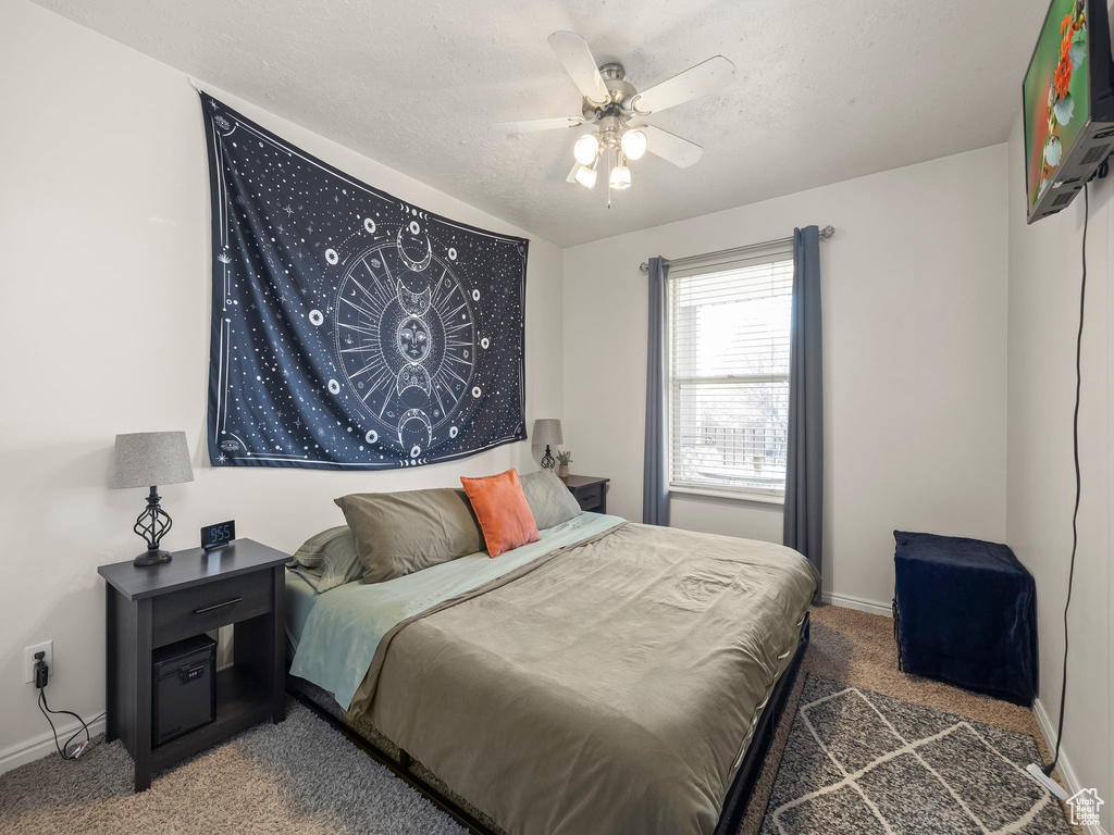 Bedroom featuring carpet flooring, a textured ceiling, baseboards, and ceiling fan