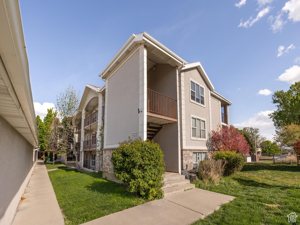 View of side of home featuring stucco siding, a yard, and brick siding