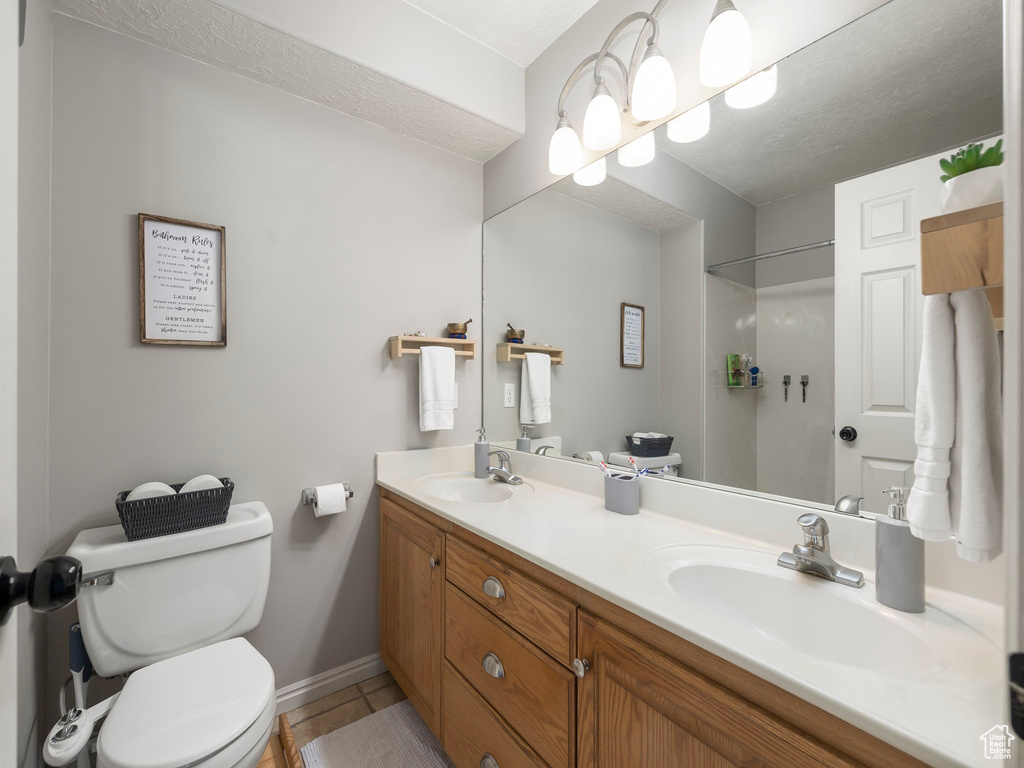 Bathroom with baseboards, a sink, double vanity, and toilet