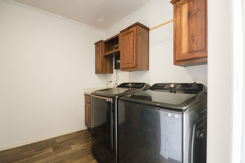 Washroom with separate washer and dryer, cabinet space, dark wood-type flooring, ornamental molding, and baseboards