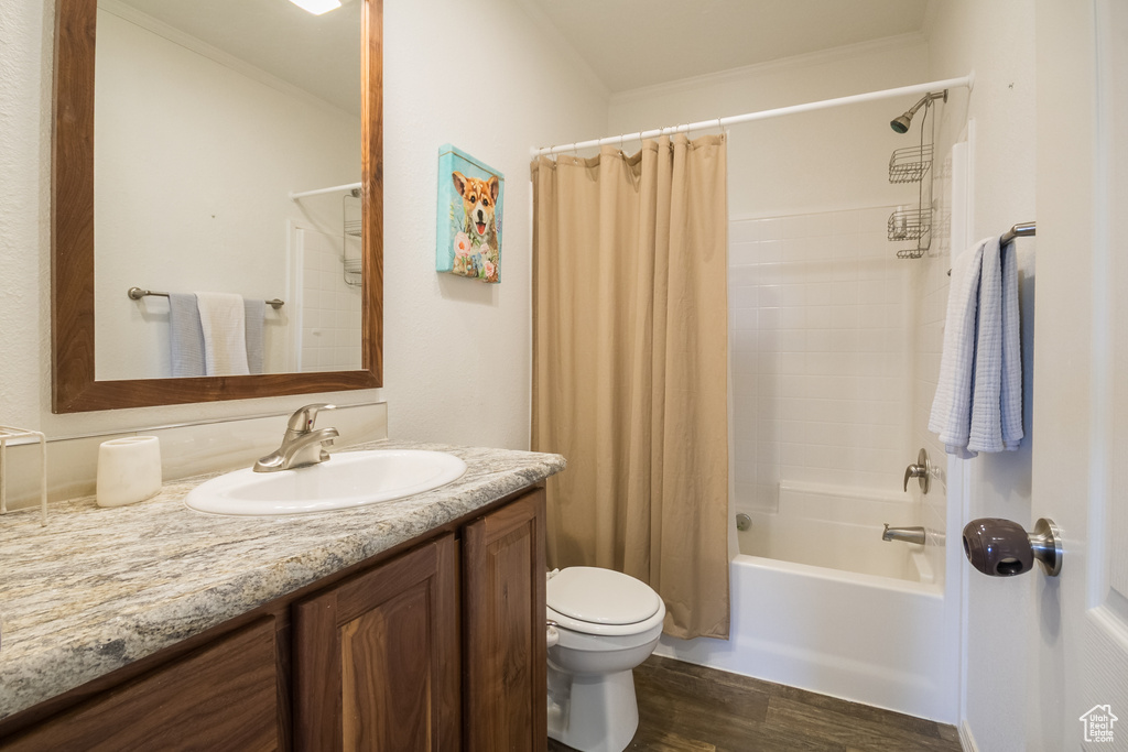 Full bath with vanity, wood finished floors, toilet, shower / tub combo, and crown molding