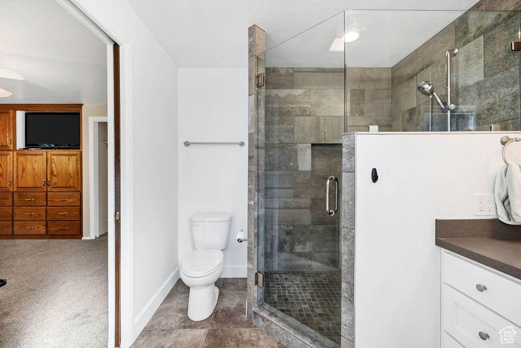 Bathroom with vanity, baseboards, a shower stall, and toilet