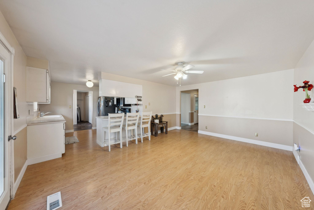 Living area featuring baseboards, ceiling fan, light wood-type flooring, and visible vents