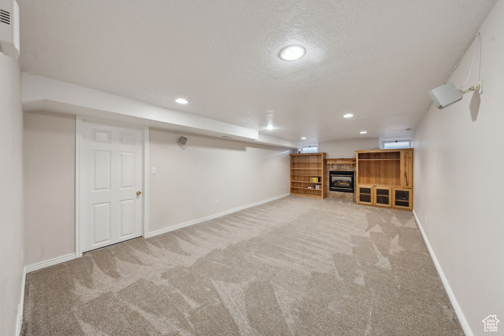 Finished basement featuring baseboards, recessed lighting, a textured ceiling, and light colored carpet