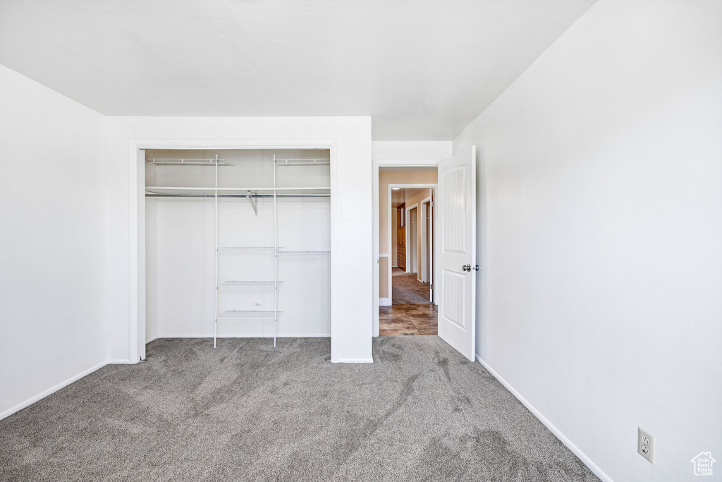 Unfurnished bedroom with carpet floors, baseboards, and a closet