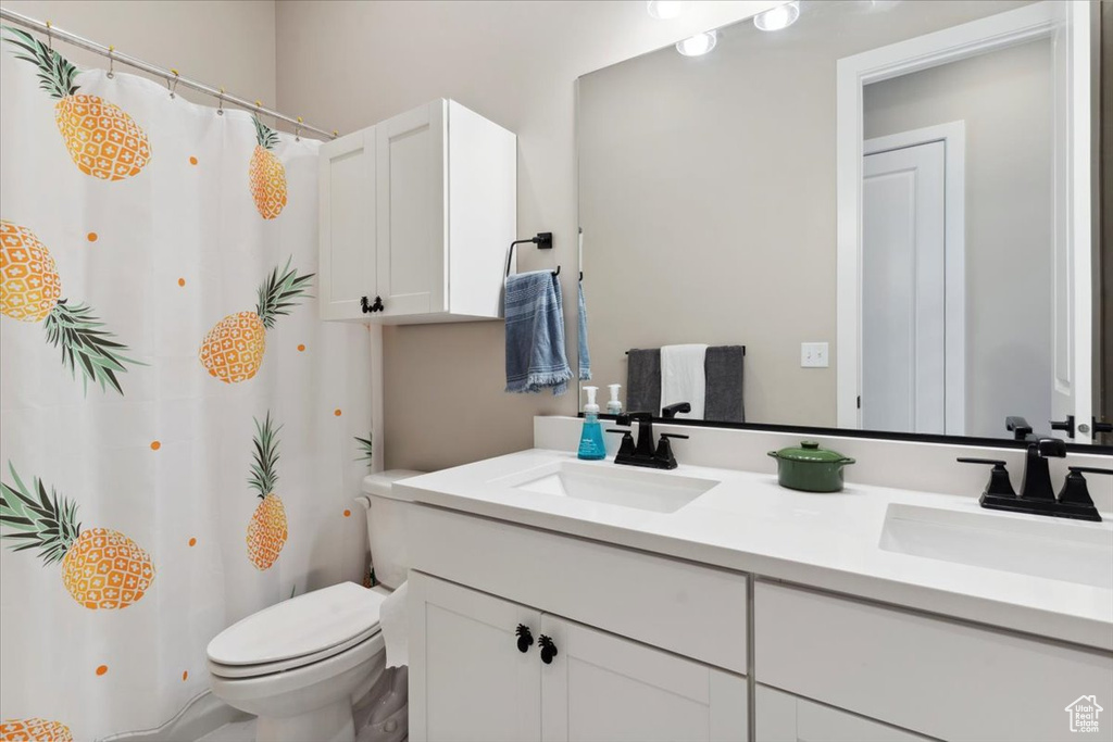 Full bath with toilet, a shower with curtain, double vanity, and a sink
