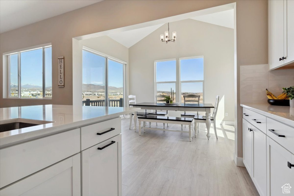 Kitchen with an inviting chandelier, light countertops, and a healthy amount of sunlight