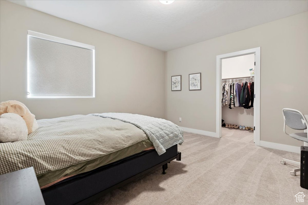 Bedroom with light carpet, a spacious closet, baseboards, and a closet