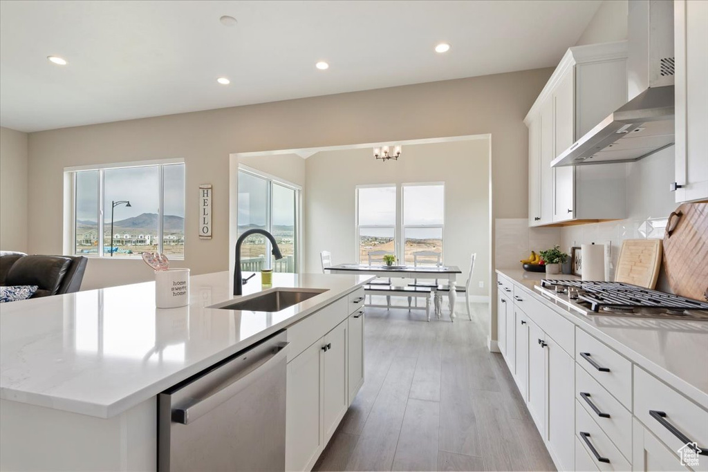 Kitchen with a sink, appliances with stainless steel finishes, wall chimney exhaust hood, healthy amount of natural light, and recessed lighting