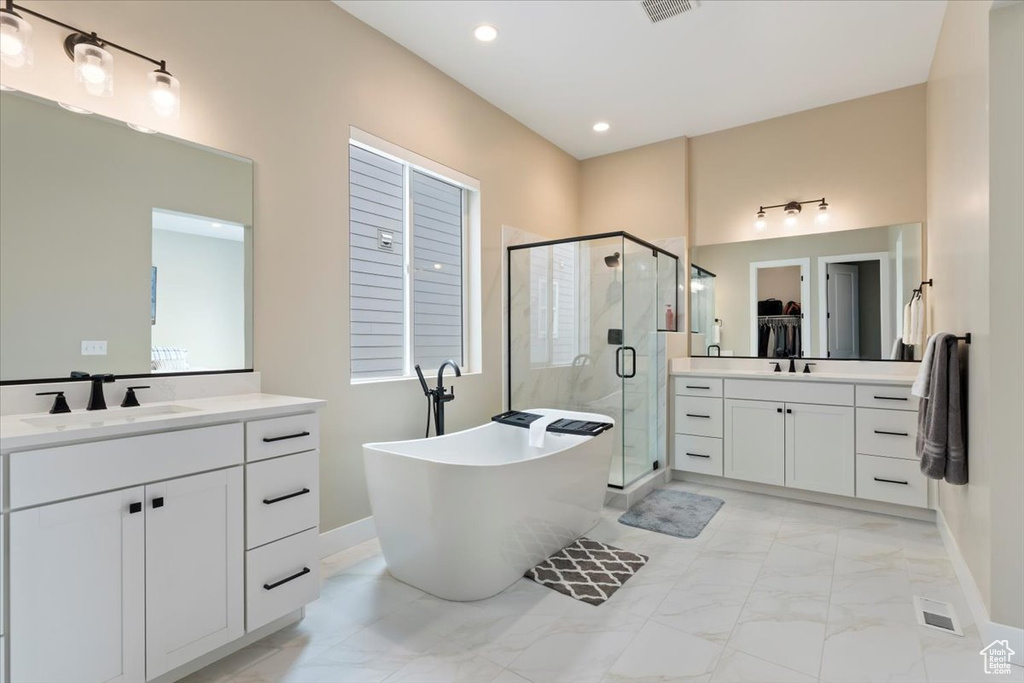 Bathroom with marble finish flooring, a shower stall, a freestanding bath, two vanities, and baseboards