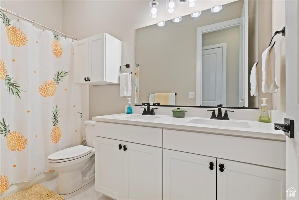 Full bath with toilet, double vanity, and a shower with shower curtain