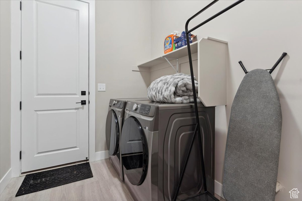 Laundry area with baseboards, separate washer and dryer, light wood finished floors, and laundry area