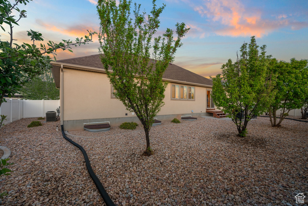 Back of property with central AC, a shingled roof, a fenced backyard, and stucco siding