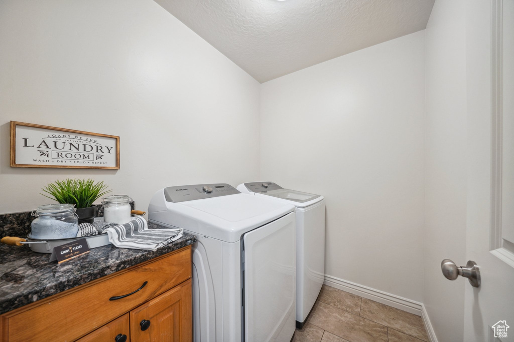 Laundry room with baseboards, laundry area, washing machine and dryer, and a textured ceiling