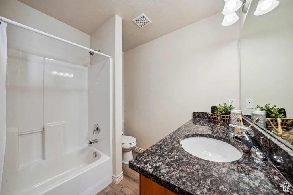 Bathroom with vanity, toilet, tub / shower combination, wood finished floors, and visible vents
