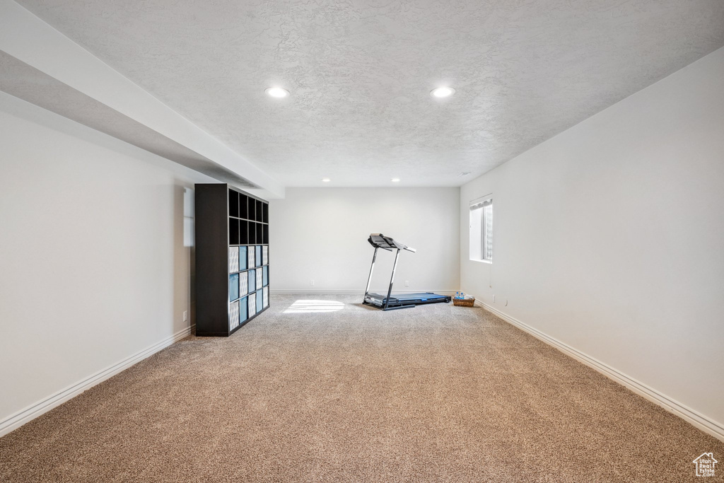 Exercise area featuring recessed lighting, baseboards, light carpet, and a textured ceiling