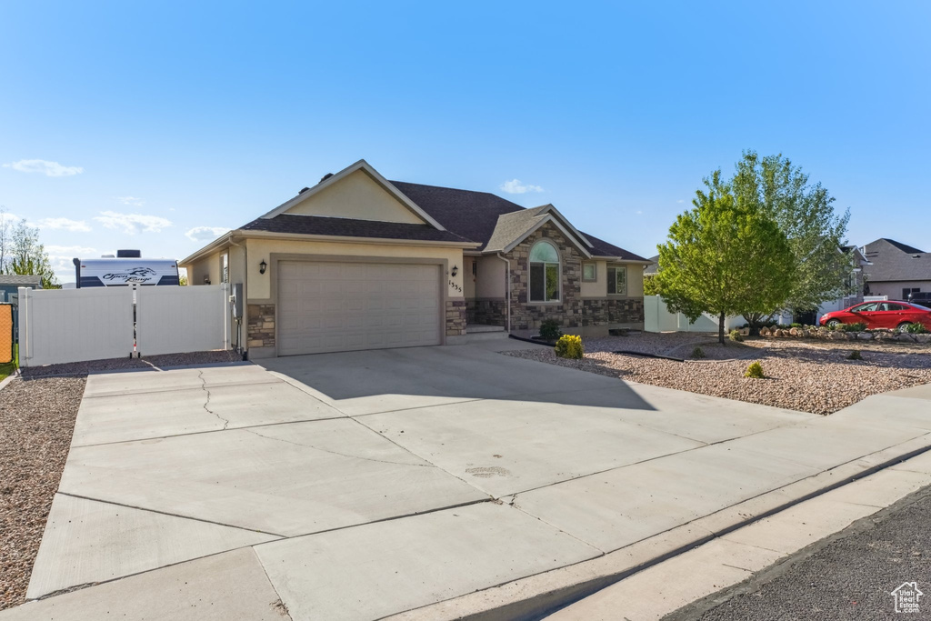 Single story home featuring driveway, a garage, fence, stone siding, and stucco siding