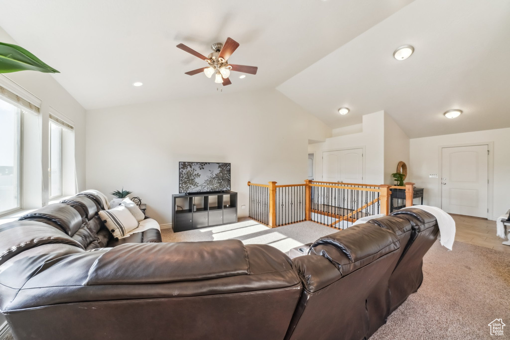 Carpeted living area with a ceiling fan and vaulted ceiling