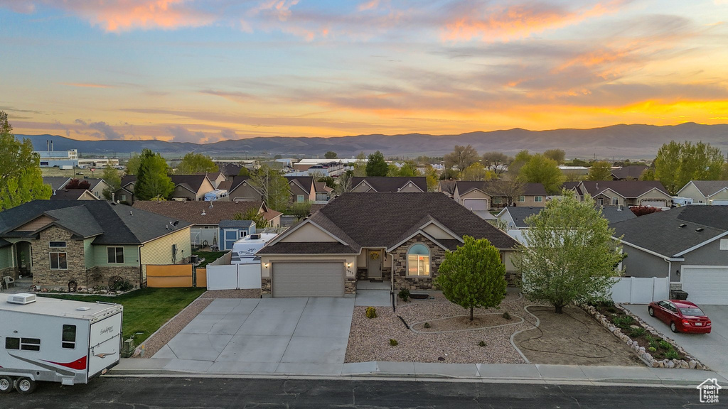 View of front facade with a residential view, fence, a mountain view, and concrete driveway